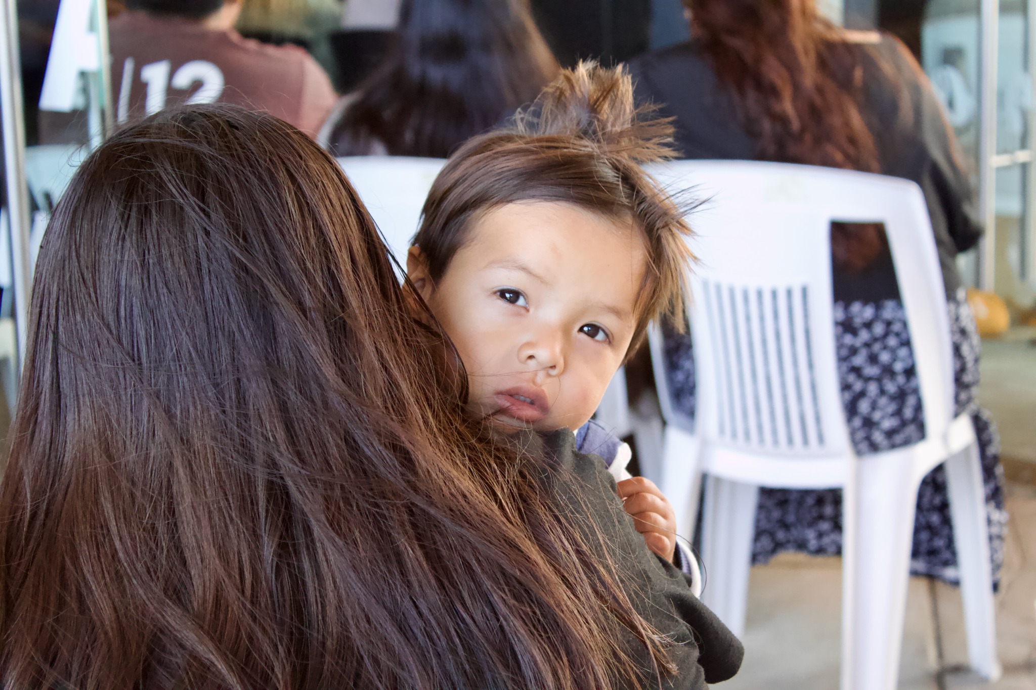 Child looking over an adult’s shoulder